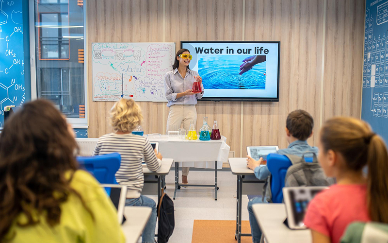 Teacher using interactive display for hybrid science lesson delivery.