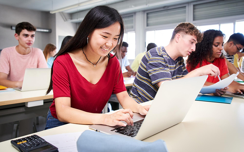 Student working on laptop during active AI higher education class.
